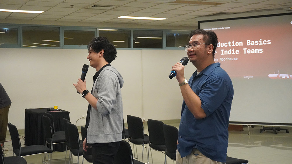 A photo of Rifkie and Lucky from IGG speaking to attendees in Jakarta with mics.