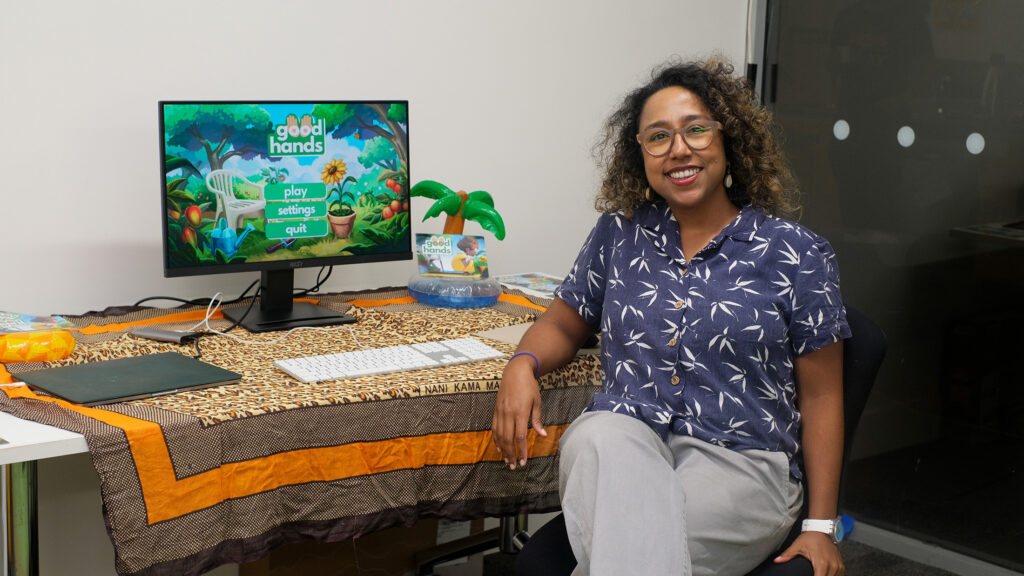 A photo of Neema Iyer next to her set up of Good Hands at WIP Night.